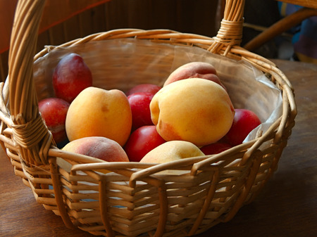 Shallow depth of field shot of a wicker basket full of apricots and plumsの写真素材