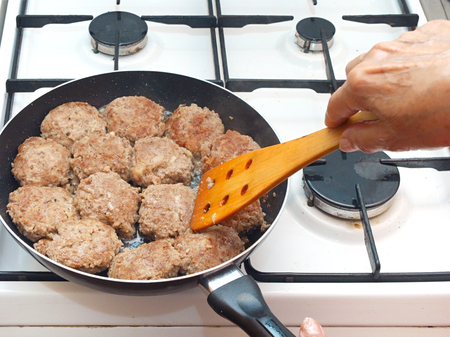 Closeup opf female hand cooking cutlets on the frying panの写真素材
