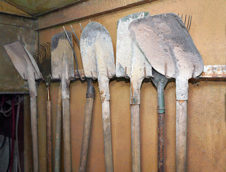Dirty used shovels hanging on a metal wall in the garageの写真素材