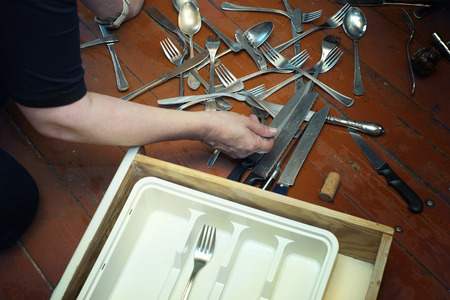 Woman and a silverware in mess on the floorの写真素材