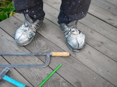 A worker standing in dirty shoes on the wooden floor next to the hand tools,の写真素材