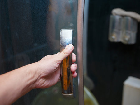 Human hand opening a shower cabin door, closeup shot