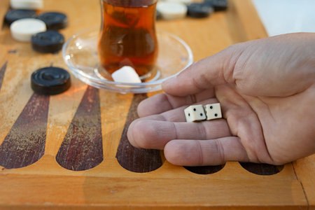 Closeup of a hand dropping dice, while playing backgammon and drinking tea