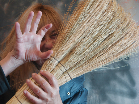 Emotional portrait of a blond woman with broom, studio shotの写真素材