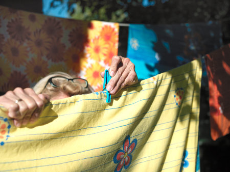 Outdoor closeup of female hands pinning washed laundry on a rope