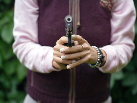 Female hands with gun, outdoor selective focus shot
