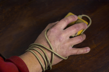 A hand wrapped with computer mouse cable, concept of addictionの写真素材