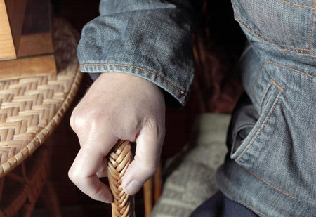 Closeup of a male hand resting on the wicker armchair