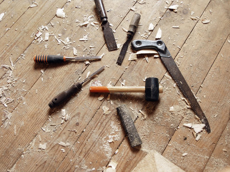 Carpenter hand tools spread out on the messy floor, above view