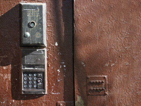 Painted metal door with different old locks and intercom, outdoor cropped closeup