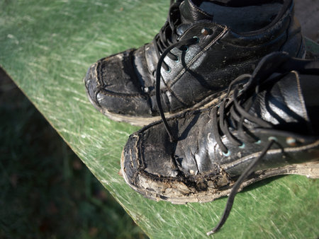 A pair of leather men shoes covered with sticky mud drying outdoors