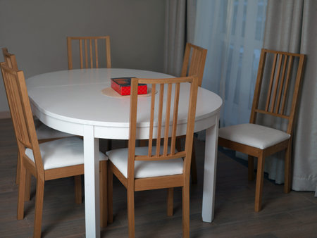A dinner table with a red box on the top and wooden chairs, indoor shot