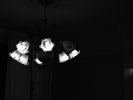 A black and white photo of a dark room with chandelier on the ceilingの写真素材
