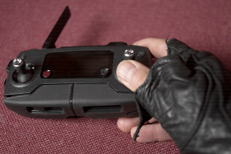 A hand wearing leather glove holding abstract remote control, on red