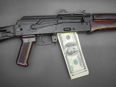 Closeup of machine gun with dollar banknotes instead of magazine