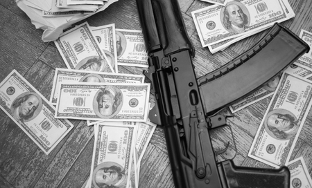 Overhead shot of a gun machine and american dollars spread out the floor, selective focus in black...