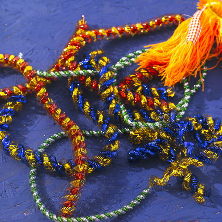 Colorful messy tinsel, placed on the blue painted background. Square composition