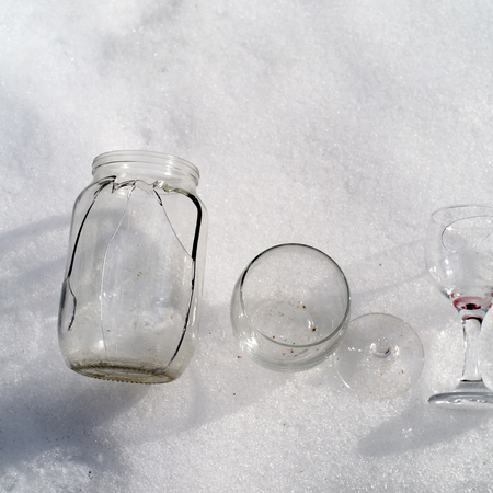 Damaged jar and broken wine glasses placed on the snow, square outdoor shotの写真素材