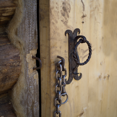 Massive steel chain on a handle of open wooden door, outdoor close-upの写真素材