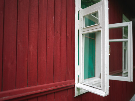 Wooden house painted in red with widely open windows
