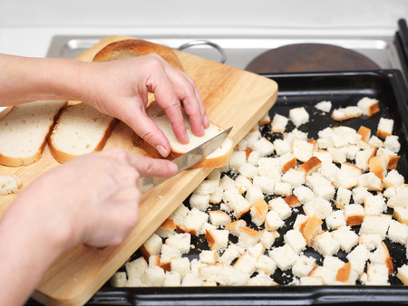 Female hands with knife preparing bread crumbs, indoor close-up