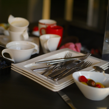 Mess in a litchen after a meal finished with a pile of unwashed dishware