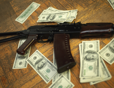 Machine gun and dollar banknotes spread out on a floorの写真素材