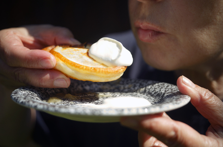 Close-up of a woman about to eat a pancake, holding a plate in her hands, outdoor shotの写真素材