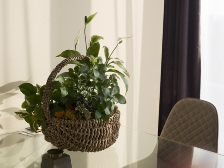 A wicker basket with beautiful bouquet, placed on a table, interior close-upの写真素材