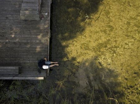 bird eye view of a fisherman sitting on the wooden jettyの写真素材