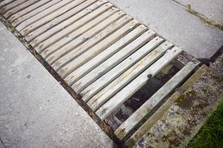 A gap in asphalt repaired with wooden planks, outdoor close-up