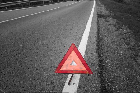 Triangle warning road sign on asphalt, selective color shotの写真素材