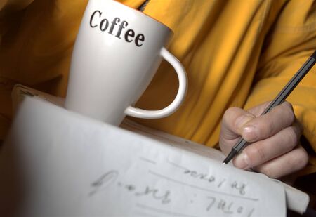A man making some calculations on a paper while having coffee, studio close-up