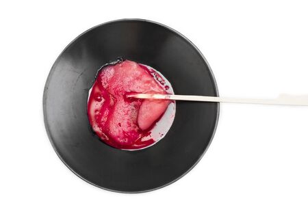 Overhead shot of a melting lollipop on a saucer, on white