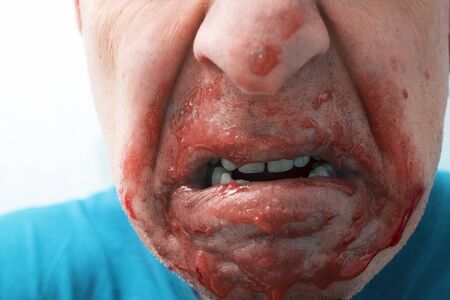 Cropped portrait of a man with open mouth and leaking blood or jamの写真素材