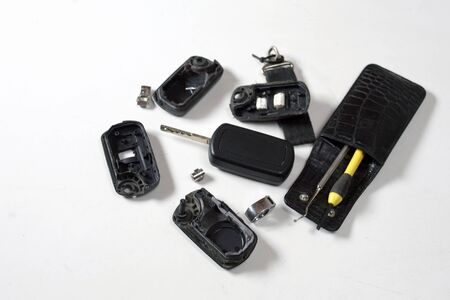 Disasembled ignition keys ans hand tools on a white desk, indoor close-up