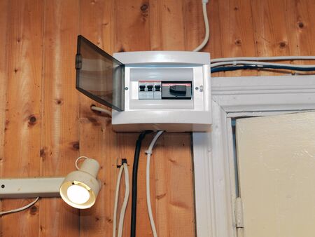 A fuse box mounted on the wooden wall, indoor close-up