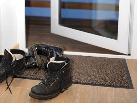 Bunch of winter boots abandoned close to doorway, indoor close-up image