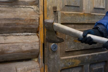 Closeup of a hand with axe trying to open a door, outside shot