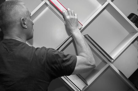 Selective color shot of a man picking a book from a shelf