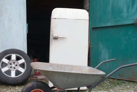 Old fridge about to be loaded on a wheelbarrow, outdoor shot