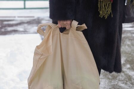 A woman wearing fur coat holding a shopping bag, winter scene, concept of consumerism
