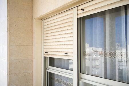 Part of the window shut with metal blinds, outdoor closeup