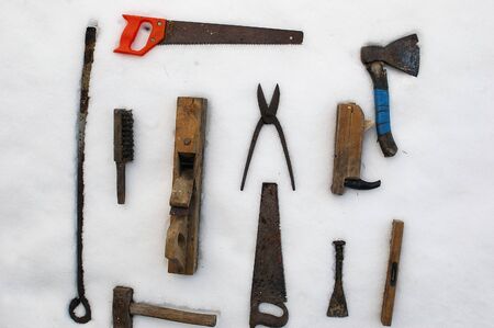 collection of vinatge carpentry tools placed on the snow, overhead shot