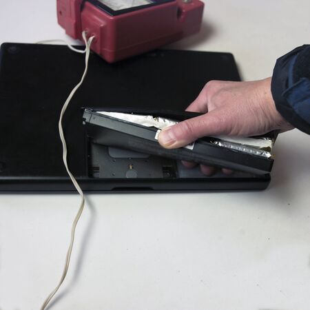 closeup of a hand rerplacing a damaged laptop battery