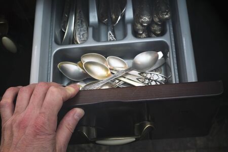 Hand opening a cupboard with vintage silverware, indoor closeupの写真素材