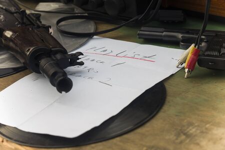 DJ playlist and firearm next to th musical equipment, concept of gangster musicの写真素材
