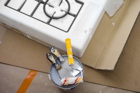 Brand new stove, trovels an paintbrushes on the floor, indoor shot