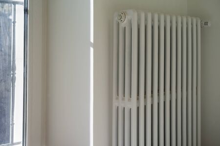 A radiator hanging on the wall next to a window, indoor closeupの写真素材
