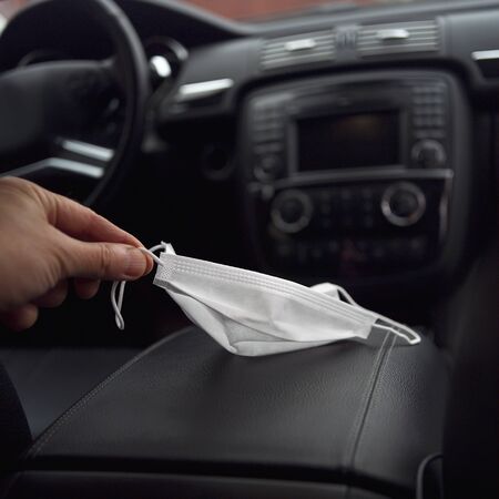 A car interior and a male hand holding a medicine maskの写真素材